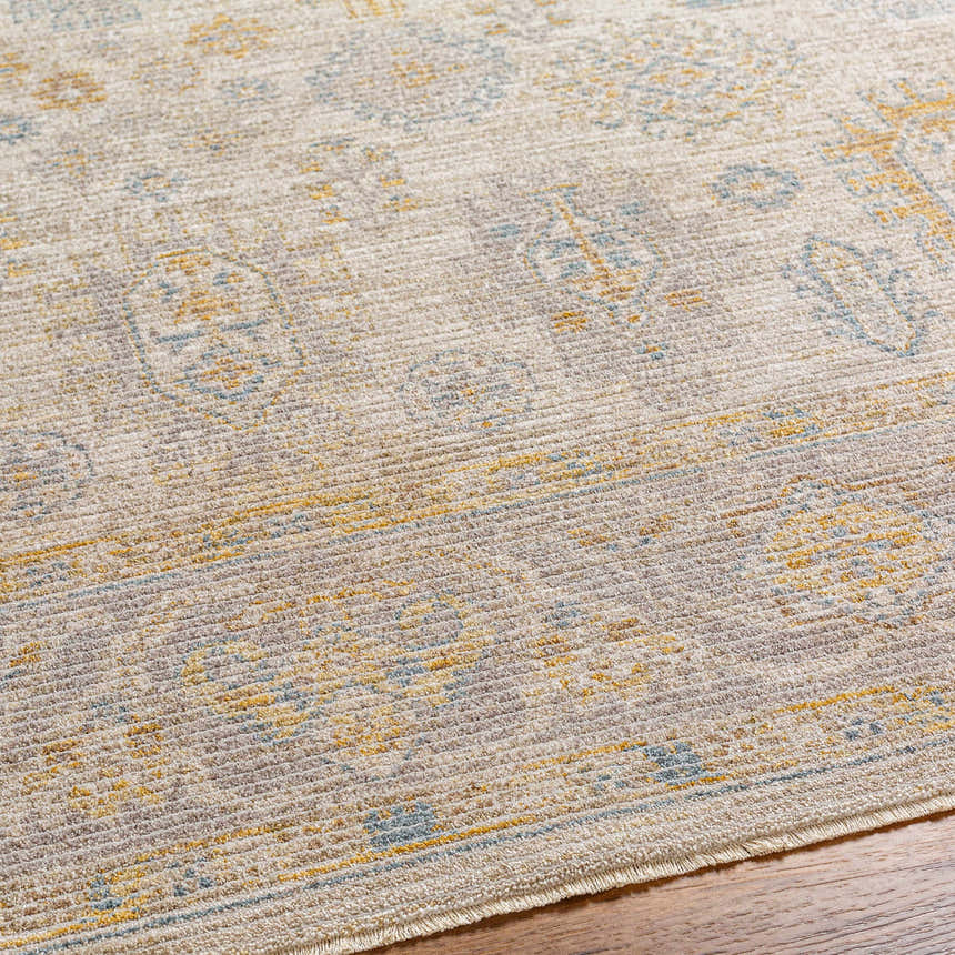Close-up of the Ayele rug showing its traditional pattern in charcoal, mustard, and gray on a textured polyester weave. Texture