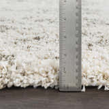 Close-up of the Aylett Beige Trellis Shag Rug showing its plush texture and height with a ruler. Colors are ivory, beige, and charcoal. Pile