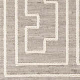 Close-up of the Azra Tasseled Jute & Wool Rug. Charcoal and cream rug with a geometric pattern and braided tassels. Swatch