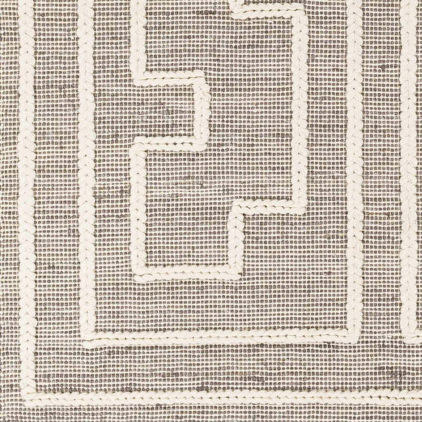 Close-up of the Azra Tasseled Jute & Wool Rug. Charcoal and cream rug with a geometric pattern and braided tassels. Swatch