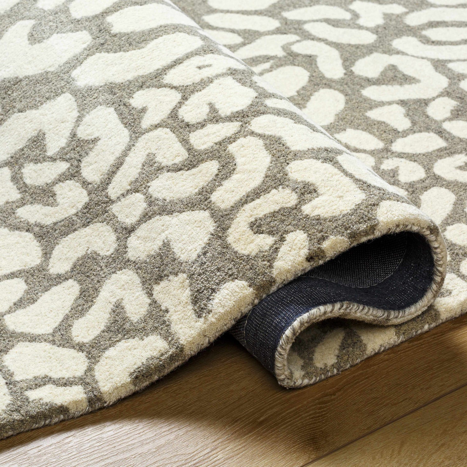Close-up of the hand-tufted Azuka Leopard Print Area Rug showing its beige and gray wool texture and runner shape. Fold