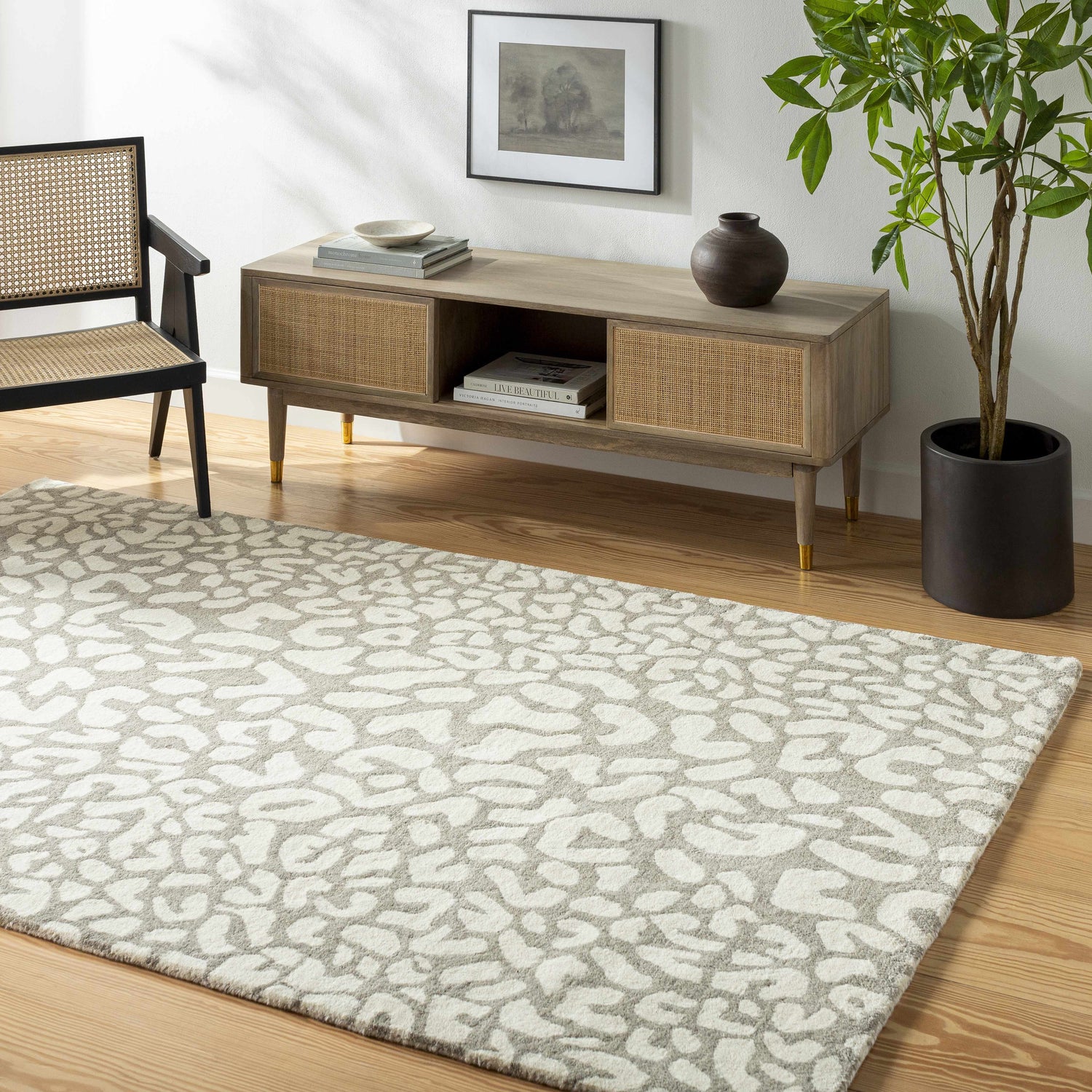 Living room scene with beige Azuka Leopard Print Area Rug, wood floors, console table, chair, and potted plant. Roomscene-Rectangle