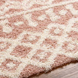 Close up of the Azura Shag Area Rug showing its geometric pattern and shag texture in dusty pink and white thatch. Texture