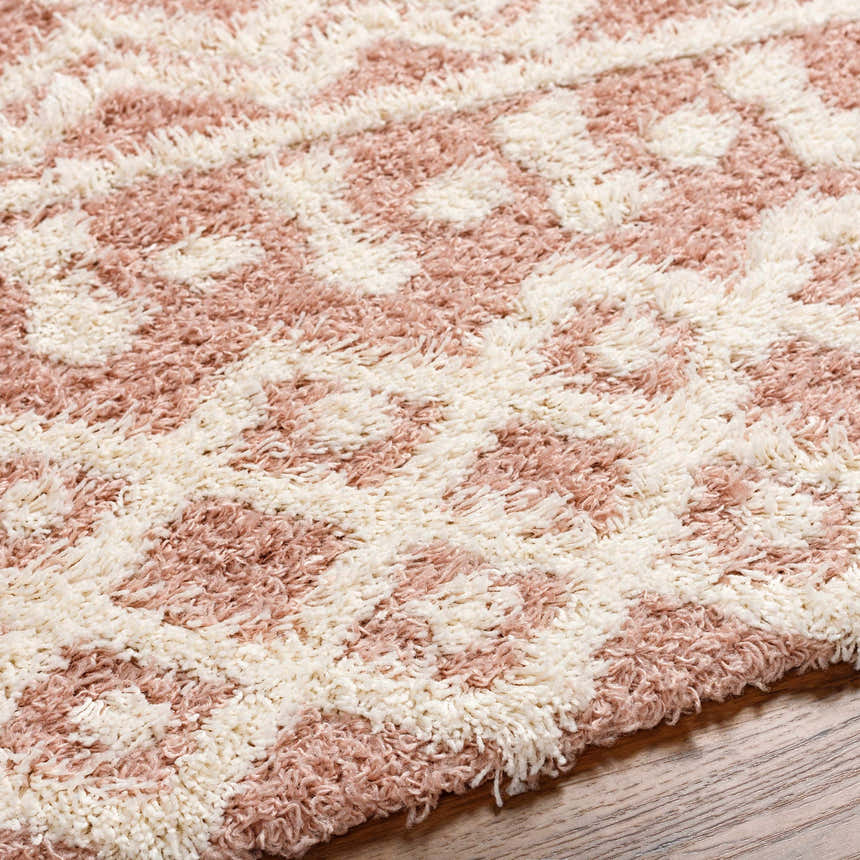 Close up of the Azura Shag Area Rug showing its geometric pattern and shag texture in dusty pink and white thatch. Texture