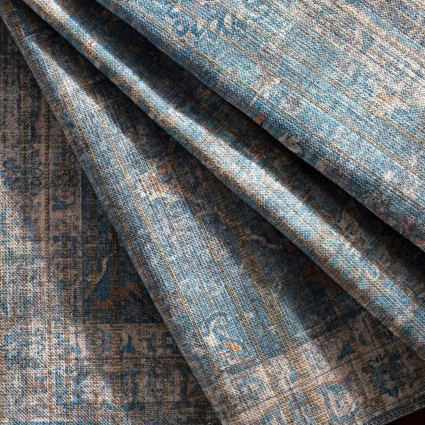 Close-up of the Bagontapay Washable Area Rug showing its blue, cream, and light brown traditional pattern and chenille texture. Fold