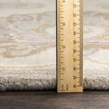 Close-up of the Conesus 1192 ivory and taupe wool rug showing its pile height with a ruler on a wood floor. Pile