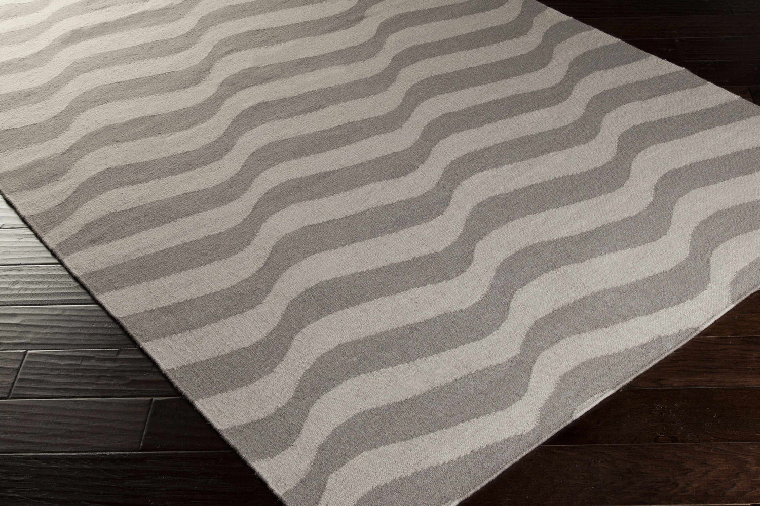Close-up of the Balsam Area Rug. Light gray and slate wavy stripes on a hand-woven wool rug. Contemporary style. Corner