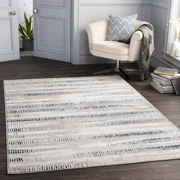 Living room scene with a cream chair and the Banana Area Rug in cream, dark blue, and gray on a dark wood floor. Roomscene-Rectangle