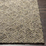 Close-up of the Barahan Area Rug. Hand-tufted wool rug in black, charcoal, ivory, and olive with a geometric diamond pattern. Front