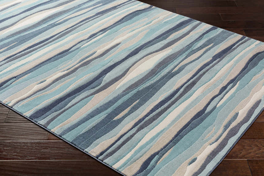 Close-up of the Basco Area Rug, a contemporary rug with aqua, charcoal, beige, and blue wavy stripes. Corner
