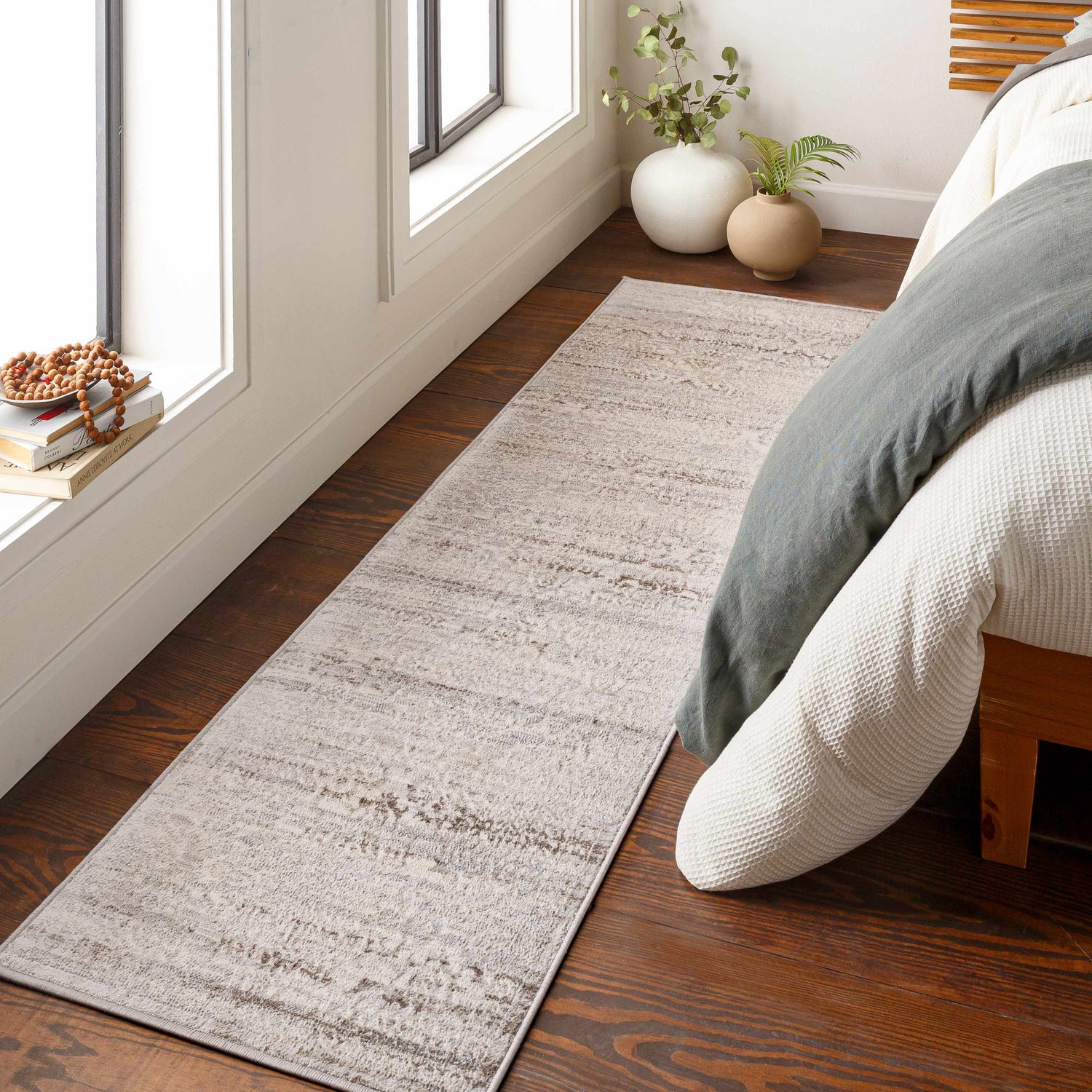 Bedroom scene with a neutral Batasan Area Rug, wood floors, and soft natural light from the window. Roomscene-Runner