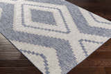 Close-up of the McCrory Pale Blue Flat Rug showing its geometric pattern and blue and off-white colors. Corner