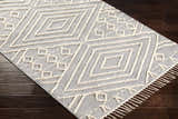 Close-up of the hand-woven Bealeton Area Rug. Cream geometric pattern on slate gray cotton with fringe detail. Corner