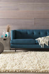 Living room scene with a cream Bedias Wool Area Carpet, blue sofa, and modern decor. Roomscene-Rectangle