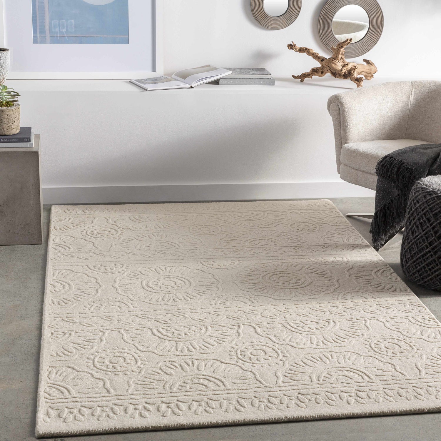Living room scene with beige Beighton Clearance Rug, light beige chair, and modern decor on a shelf. Roomscene-Rectangle