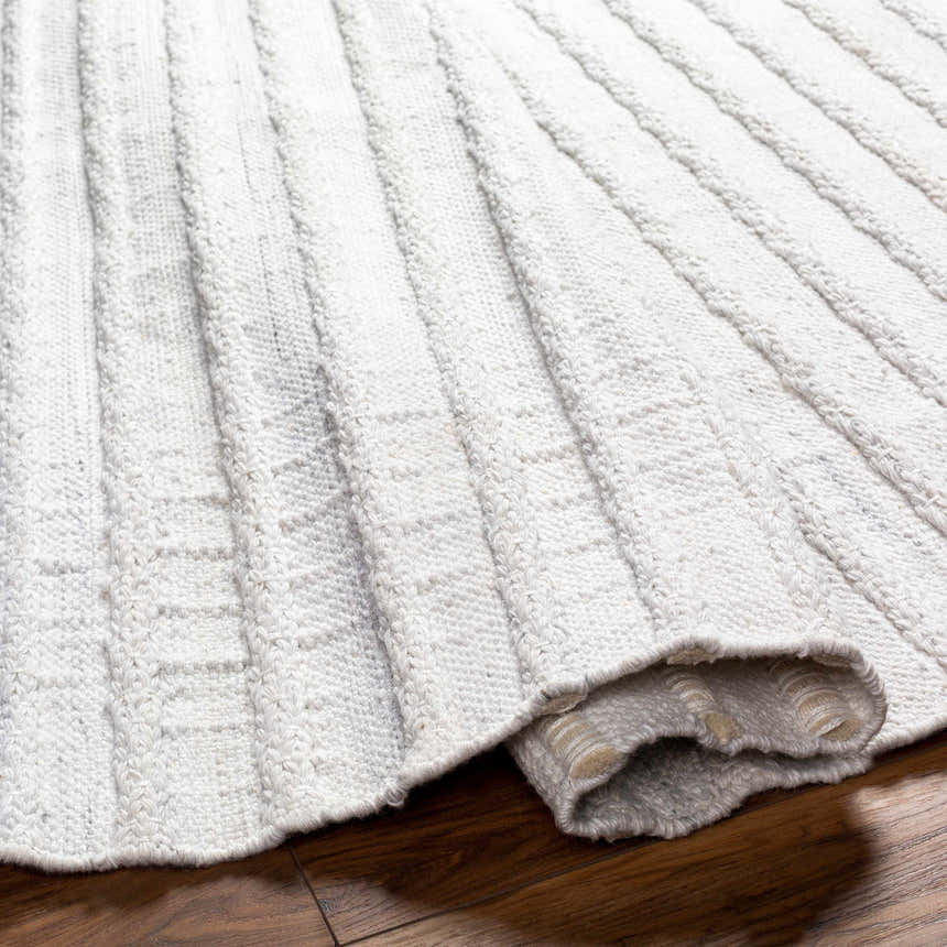 Close-up of the light gray Benek Area Rug showing its hand woven geometric pattern and recycled PET yarn texture. Fold