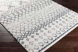 Close up of the Benezett Area Rug. White shag rug with gray bohemian pattern on dark wood floor. Corner