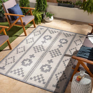 Outdoor patio scene with the Besao Indoor Outdoor Rug, wood chairs, plants, and travertine tile flooring. Roomscene-Rectangle