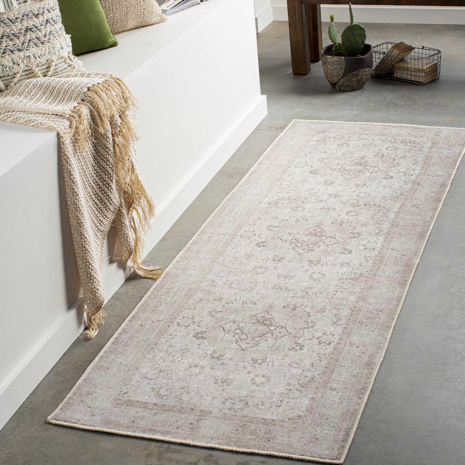 Hallway scene with a beige Bethany Vintage Flat Pile Washable Rug, throw blanket, pillows, and a cactus on a concrete floor. Roomscene-Runner
