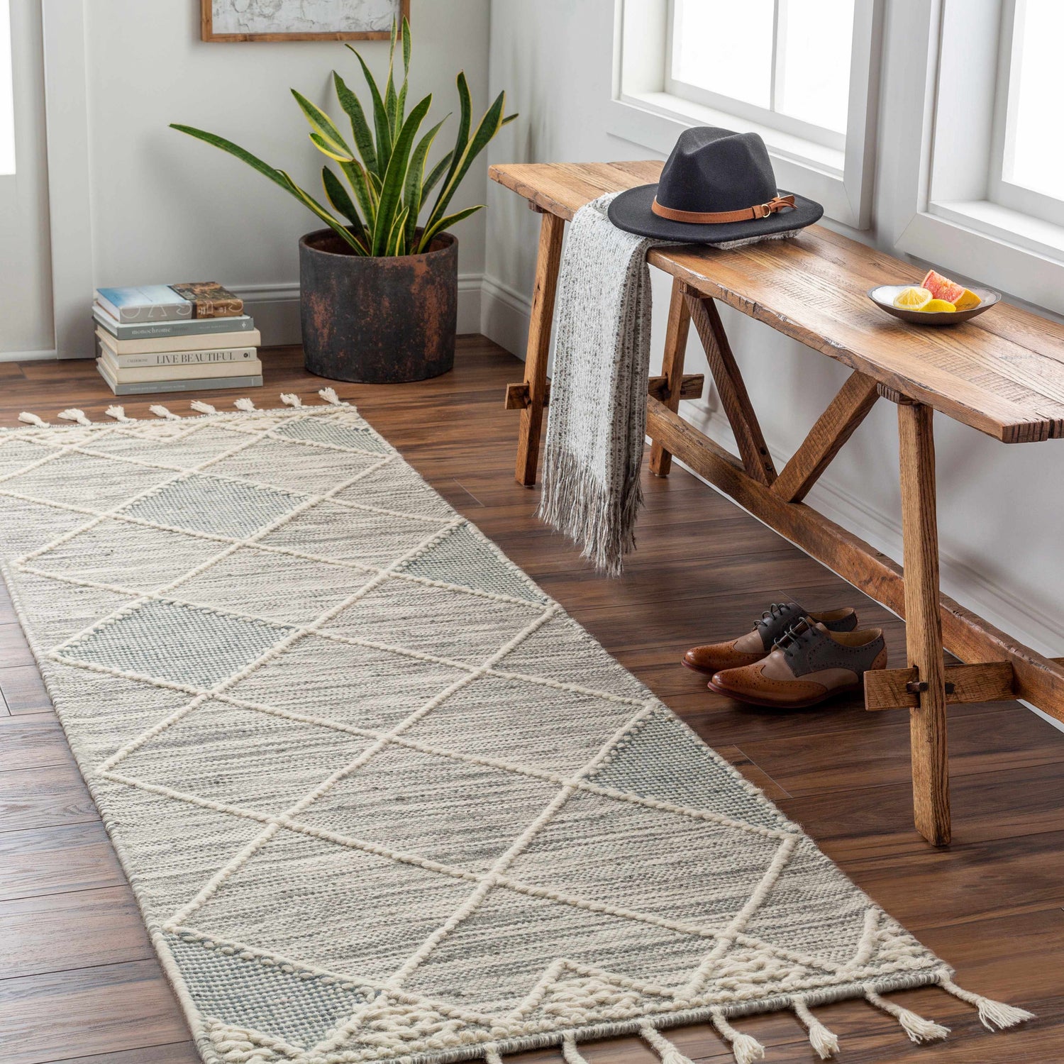 Entryway scene with a Bicos Tasseled Jute Rug, wooden bench, hat, and shoes on a wood floor. Farmhouse style. Roomscene-Runner