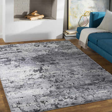 Living room scene with a Bilston Boutique Thick Luxe Rug in black, charcoal, gray, and ivory. Blue sofa and fireplace. Roomscene-Rectangle