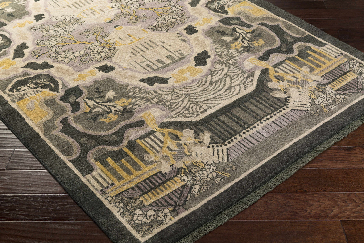Close-up of the Binger Premium Area Rug. Hand-knotted wool rug with a vintage-inspired design in dark green, ivory, gray, and tan. Corner