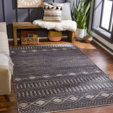 Living room scene with black Bithlo Jute Carpet, beige sofa, wood bench, plants, and geometric decor. Roomscene-Rectangle