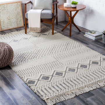 Living room scene with a cream and black geometric Blakeview Wool Rug, wood chair, and side table. Roomscene-Rectangle