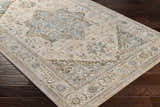 Close-up of Ballisodare Thick Luxe Boutique Rug showing a traditional design in light beige, sage, and teal on dark wood floors. Corner