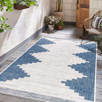 Outdoor patio scene with the Djugun Navy Indoor & Outdoor Area Rug, plants, and a wicker chair. Roomscene-Rectangle