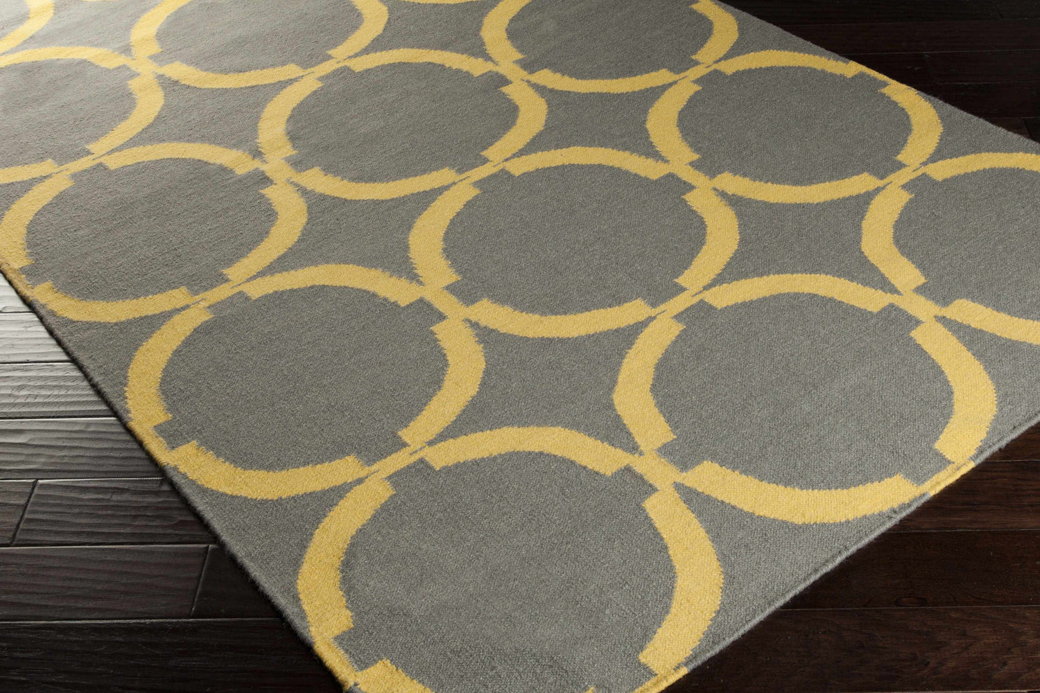 Close-up of the Bloomer Area Rug featuring a gray background and mustard yellow geometric circle pattern. Corner