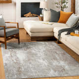Living room with a Binabaan Abstract Area Rug in charcoal, gray, and tan. Modern sofa, chair, and fireplace create a cozy scene. Roomscene-Rectangle