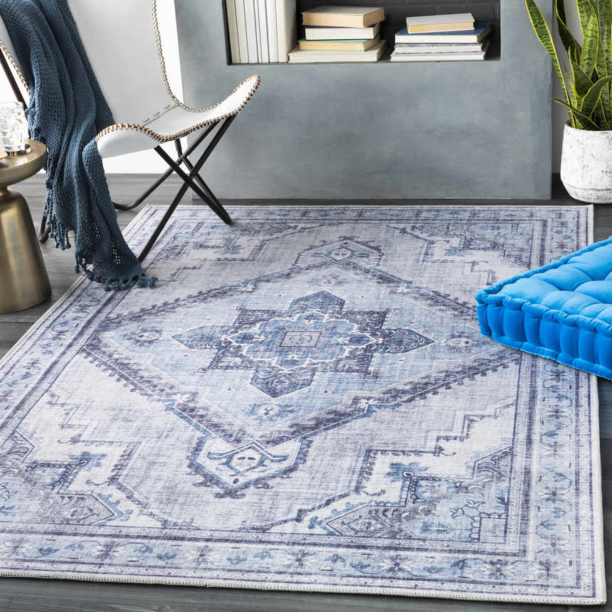 Living room scene with ivory and blue Boon Area Rug, white chair, and blue floor cushion. Roomscene-Rectangle