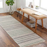 Entryway scene with a gray, beige, and sage striped Bocana Area Rug runner on wood floors. Bench with books and plant. Roomscene-Runner