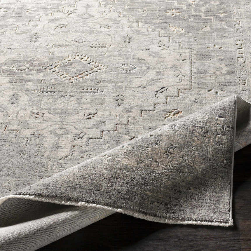 Close-up of the Boli Distressed Statement Rug, showing a gray, ivory, and light olive vintage pattern and soft, textured pile. Fold