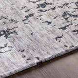 Close-up of the Bomaderry Area Carpet. Hand woven polyester rug in charcoal, light gray, and medium gray. Contemporary style. Fold