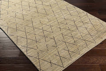 Close-up of the hand-loomed Bonogin Area Rug. Dark brown geometric pattern on a tan and olive viscose rug. Corner