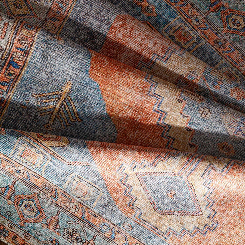 Close-up of the Bovey Washable Area Rug showing its traditional, oriental-inspired design with aqua, coral, and gray colors. Fold