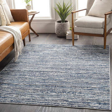 Living room scene with a Bowmansdale Striped Navy Rug, brown leather sofa, gray chair, and wood floors. Roomscene-Rectangle