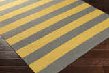 Close-up of the Boyceville Area Rug, a hand woven cotton rug with gray and mustard yellow stripes on a dark wood floor. Corner