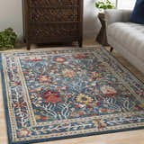Living room scene with a Neola Navy Blue Damask Area Rug, wood dresser, and gray sofa. Floral pattern in red, yellow, and tan. Roomscene-Rectangle