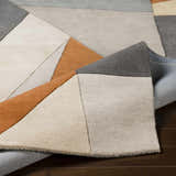 Close up of the Bracknell Modern Wool Rug featuring brick red, charcoal, gray, tan, and taupe geometric shapes. Fold