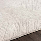 Close up of the Broadwater Luxe Rug showing its cream and light gray textured pattern on dark wood flooring. Texture