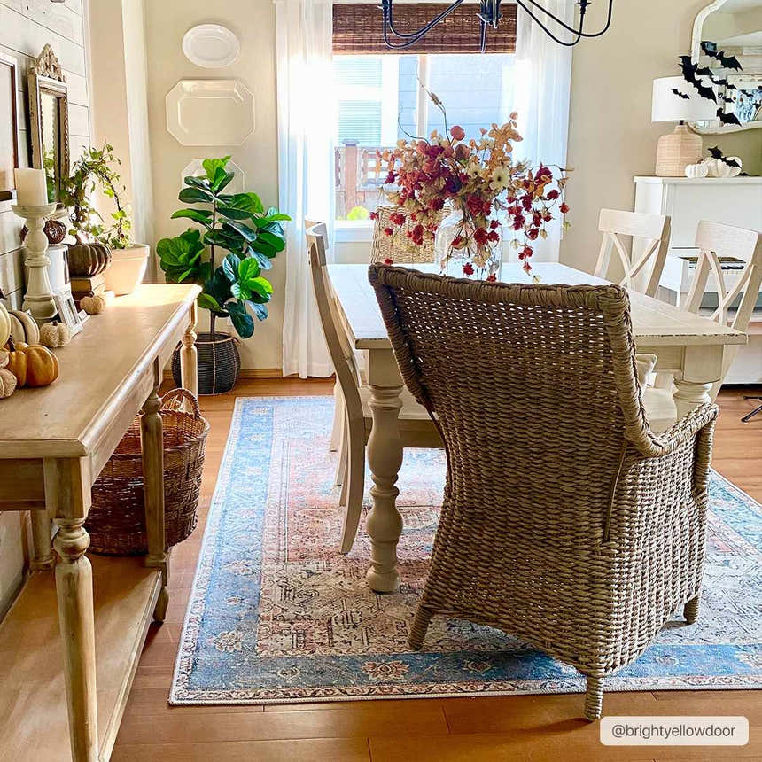 Farmhouse dining room with a Rosman Distressed Washable Area Rug in blue, beige, and brick red under a light wood table. Roomscene-Rectangle