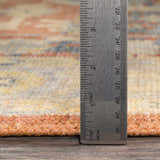 Close up of Brookeland Area Rug showing pile height with a ruler. Beige, red, and blue colors. Pile