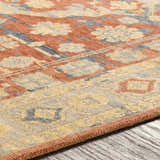 Close-up of the hand-knotted Brookeland Area Rug. Beige, brick red, and denim floral pattern on a 100% wool rug. Texture