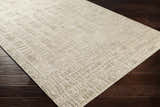 Close-up of the Burlington Clearance Rug showing its oatmeal color and geometric, hand-loomed pattern on dark wood flooring. Corner
