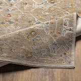 Close-up of the Barneyside Luxe Area Rug showing its brick red, cream, denim, and tan oriental pattern and textured weave. Fold
