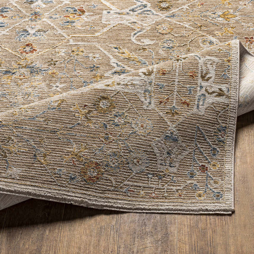 Close-up of the Barneyside Luxe Area Rug showing its brick red, cream, denim, and tan oriental pattern and textured weave. Fold