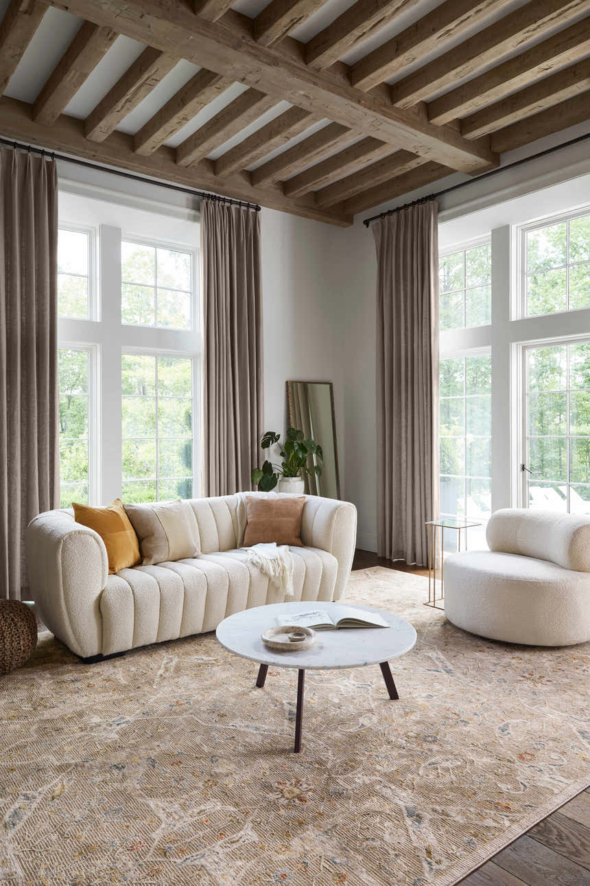 Living room with a cream sofa, round chair, and Barneyside Luxe Area Rug in tan, cream, and brick red tones. Roomscene-Rectangle